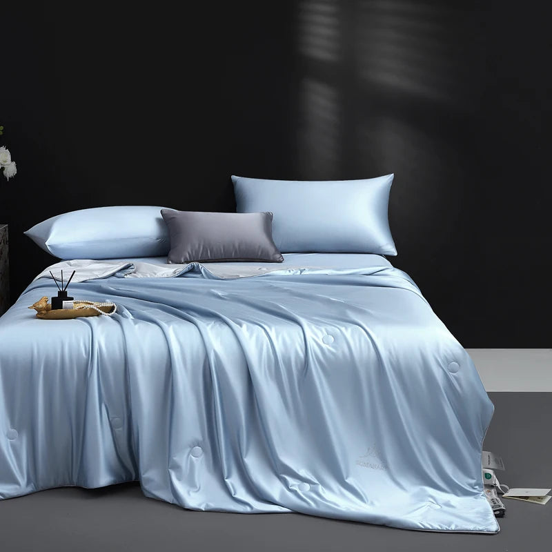 Bed with light blue bedding and pillows against a dark wall.