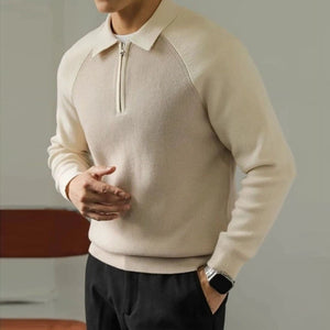 Man wearing a beige sweater with a zipper detail, standing against a neutral background.