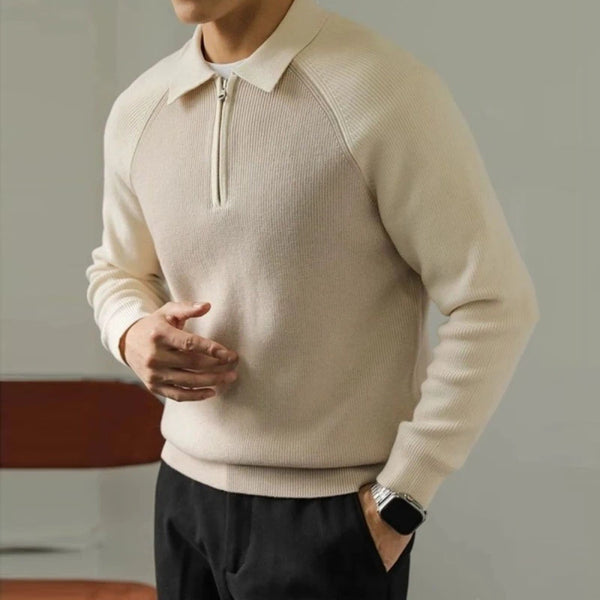 Man wearing a beige sweater with a zipper detail, standing against a neutral background.