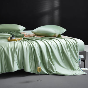 Mint green bedding set on a bed with a glass of champagne and a small table in the foreground.