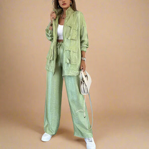Person wearing a green outfit with a jacket and pants in an indoor setting.