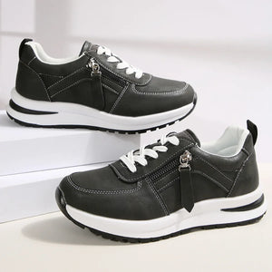 Black sneakers with white soles on a light gray background