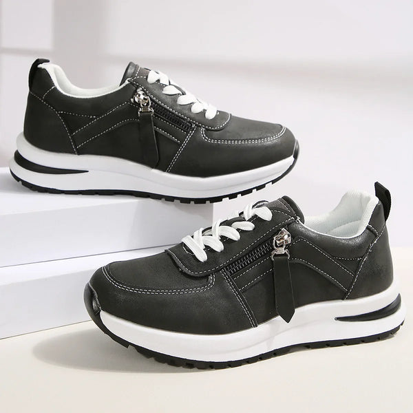 Black sneakers with white soles on a light gray background