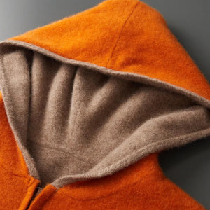 Close-up of an orange hooded garment with a gray interior lining on a gray background