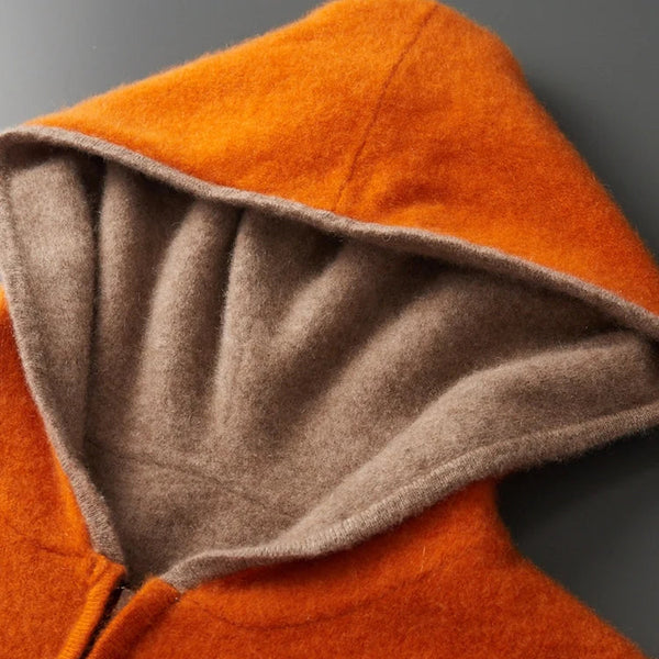 Close-up of an orange hooded garment with a gray interior lining on a gray background