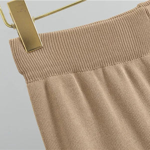 Beige pants on a gold hanger against a light gray background