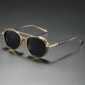 Gold-framed sunglasses with black lenses on a gray background