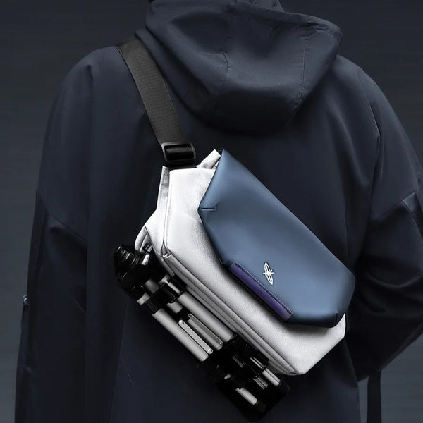 Person wearing a black jacket with a stack of folded clothes on their back against a dark background