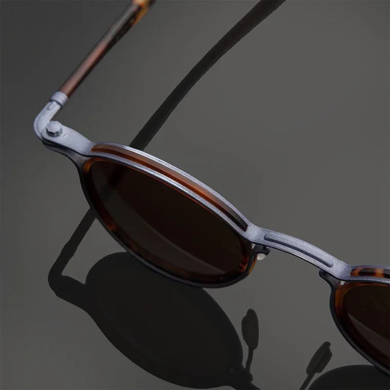 Round sunglasses with gold frame and dark lenses on a black background
