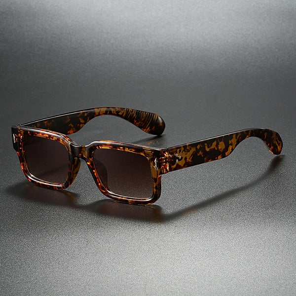 Tortoiseshell sunglasses on a reflective gray surface