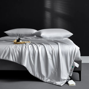 White comforter on a bed with pillows against a dark background