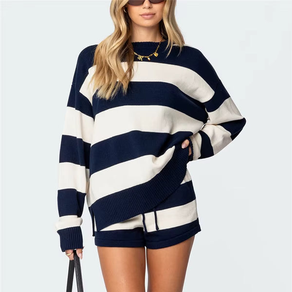 Woman wearing a navy and white striped sweater with shorts on a light gray background