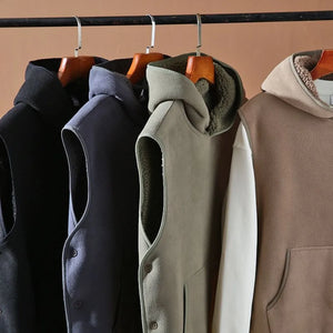 Four vests hanging on a rack against a beige wall