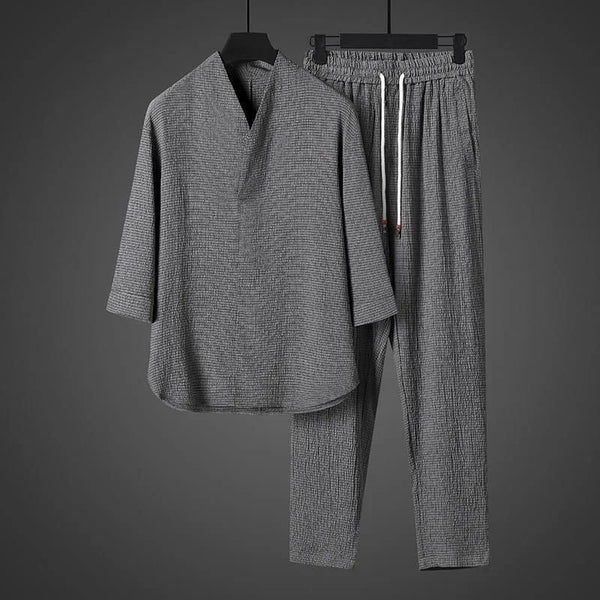 Gray checkered outfit with shirt and pants on hangers against a dark gray background