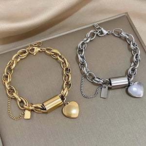 Gold and silver chain bracelets with heart charms on a neutral background