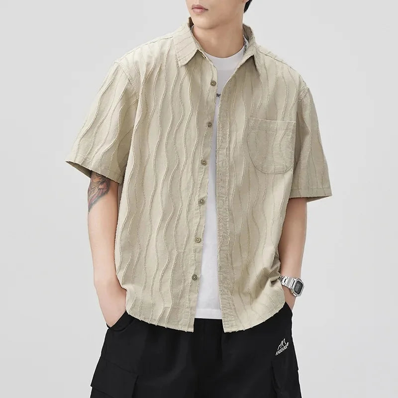 Person wearing a green patterned shirt over a white t-shirt on a light gray background