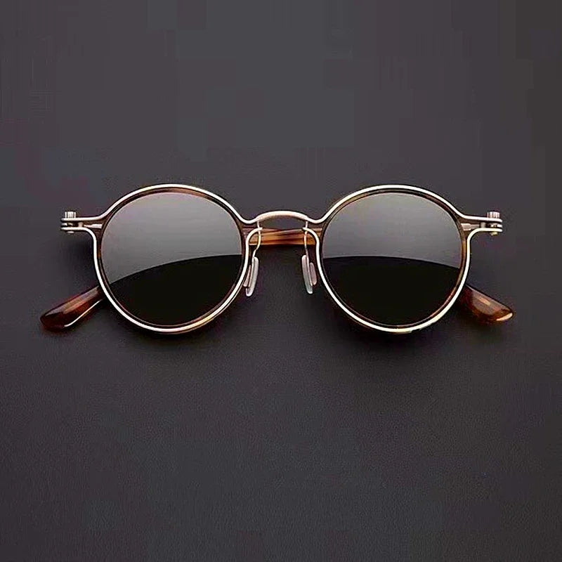 Round sunglasses with gold frame and dark lenses on a black background