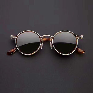 Round sunglasses with gold frame and dark lenses on a black background