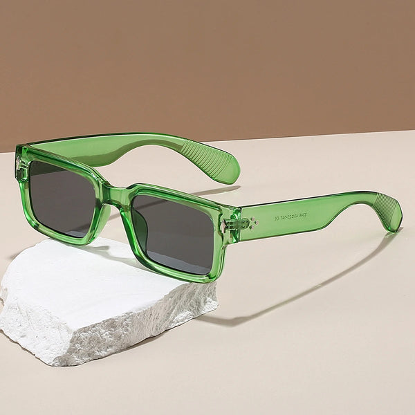 Green sunglasses with dark lenses on a beige surface