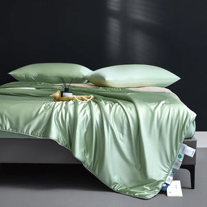 Green satin sheet set on a bed with a dark background