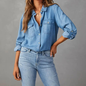 Person wearing a blue denim shirt and jeans against a gray background