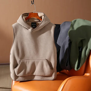 Beige sleeveless hoodie on a hanger with other clothing items in the background.