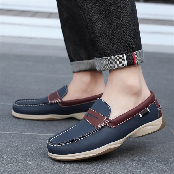 Navy and brown loafers worn with rolled-up jeans on a pavement background