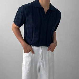 Person wearing a navy ribbed shirt and white pants against a plain background