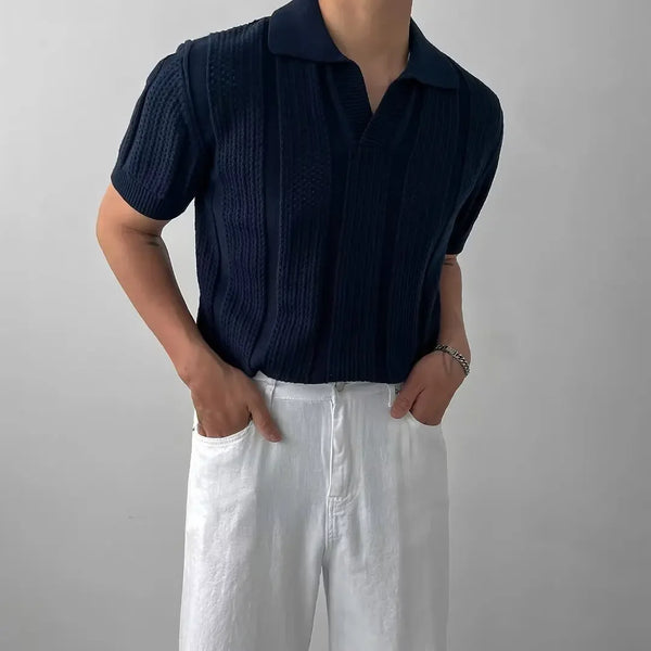 Person wearing a navy ribbed shirt and white pants against a plain background
