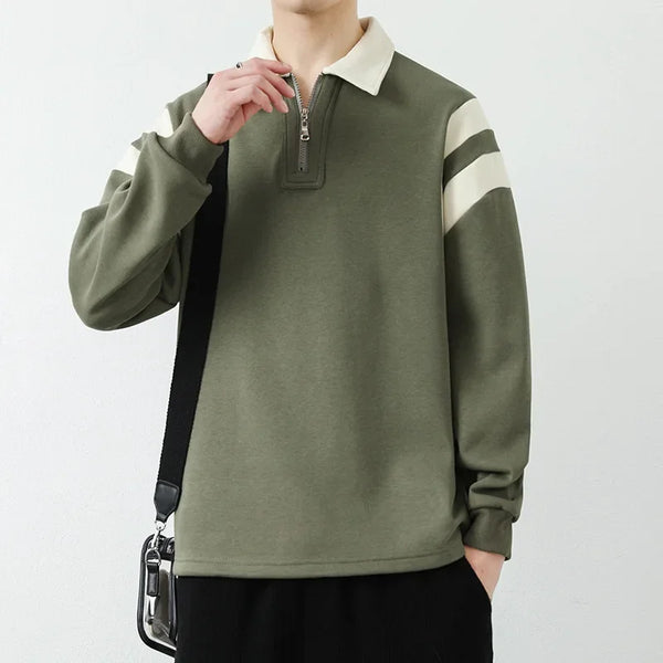 Person wearing a green sweater with white stripes on a plain background