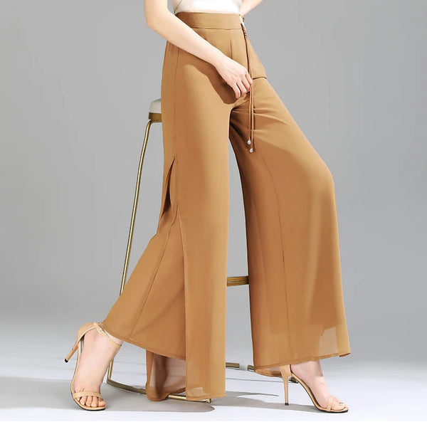 Woman wearing a white blouse and brown wide-leg pants on a gray background