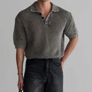 Person wearing a textured short-sleeve shirt, black shorts, and holding a black bag on a gray background