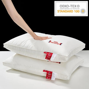 Stack of white pillows with red labels on a white surface, OEKO-TEX Standard 100 logo in the corner.