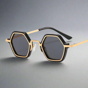 Sunglasses with gold frame and black hexagonal lenses on a white background