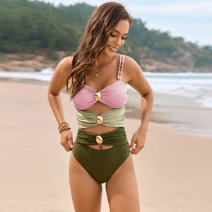 Woman wearing a two-tone bikini with pink top and green bottom on a beach.