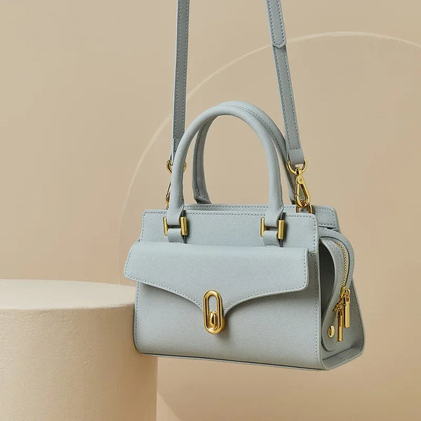 Light blue handbag with gold accents on a beige background