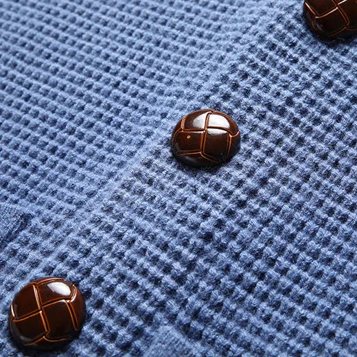Close-up of a blue textured fabric with brown buttons on a gray background