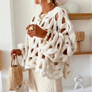 Person wearing a white crochet cover-up with a woven bag indoors.