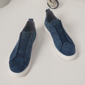 Pair of blue slip-on sneakers on a white surface