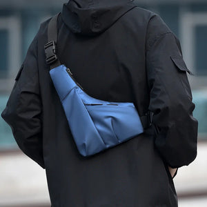 Person wearing a black jacket with a blue bag over one shoulder, blurred background