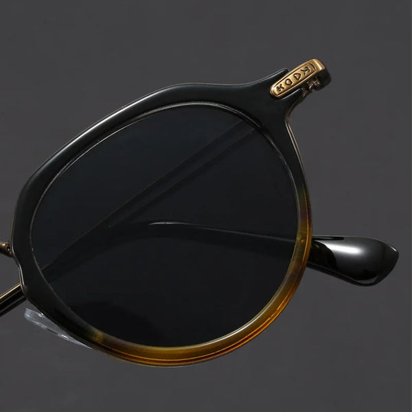 Black sunglasses with gold accents on a dark gray background