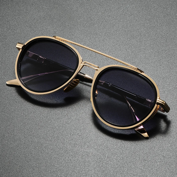 Gold-framed sunglasses with dark lenses on a gray background