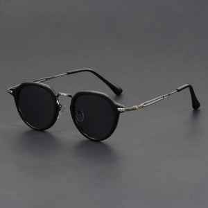 Round sunglasses with dark lenses and thin metal frames on a gray background.