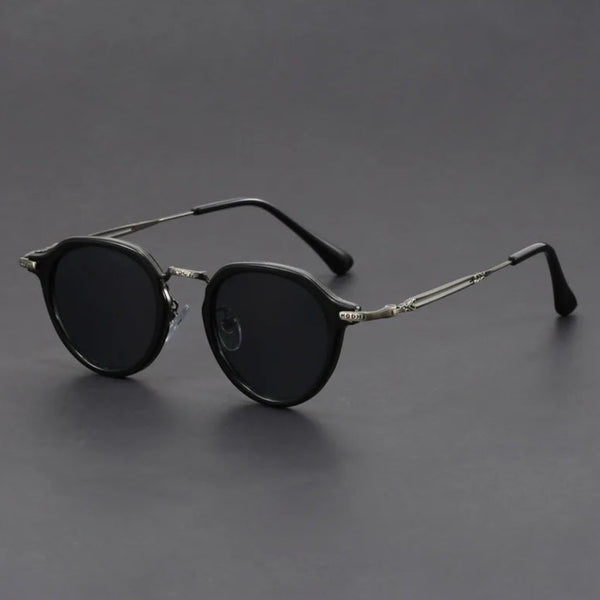 Round sunglasses with dark lenses and thin metal frames on a gray background.