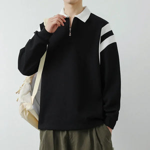 Person wearing a black sweater with white stripes on the sleeves against a plain background