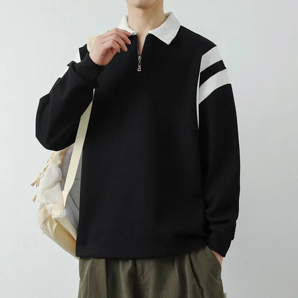 Person wearing a black sweater with white stripes on the sleeves against a plain background