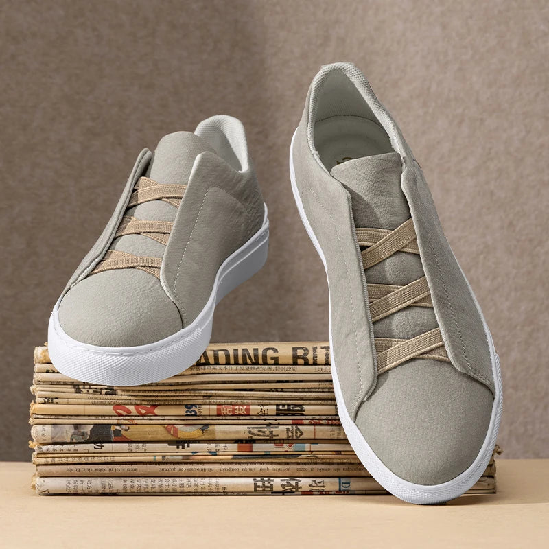 Gray slip-on sneakers on a stack of newspapers with a brown background