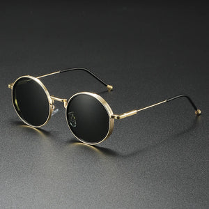 Round sunglasses with gold frame and black lenses on a dark gray background