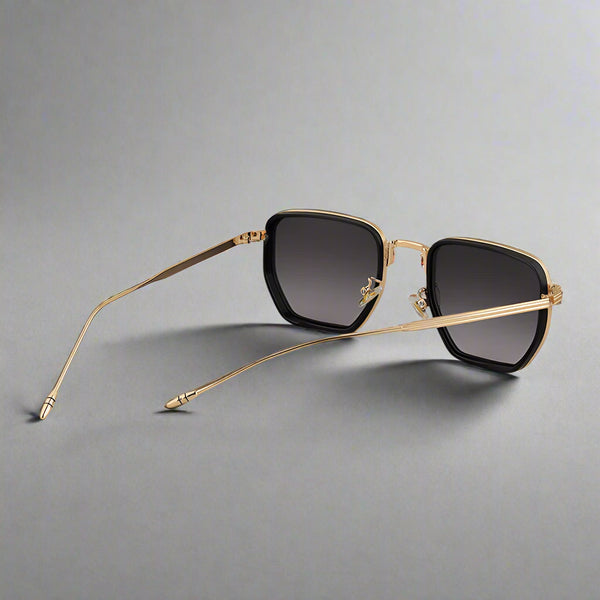Gold-framed sunglasses with black lenses on a light gray background