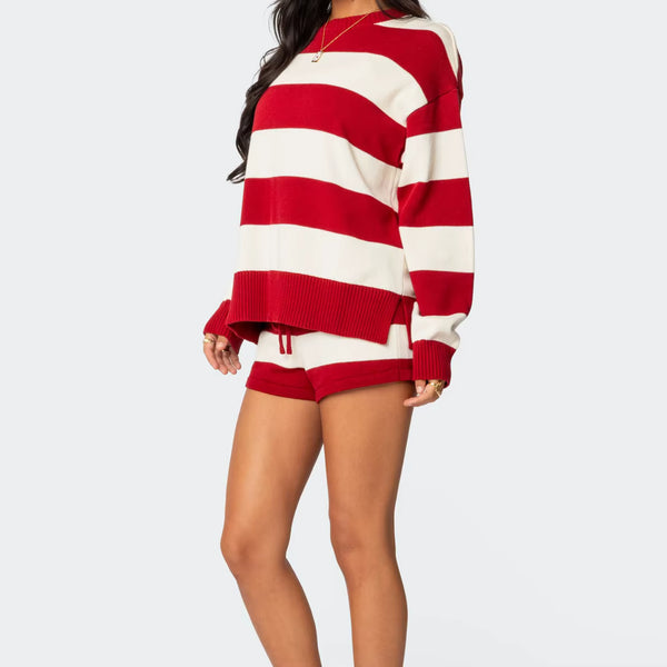 Person wearing a red and white striped sweater and shorts on a light gray background